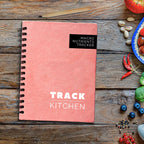 Salmon Pink coil bound nutrition journal titled 'Macro Nutrients Tracker' on a wooden surface with food ingredients.